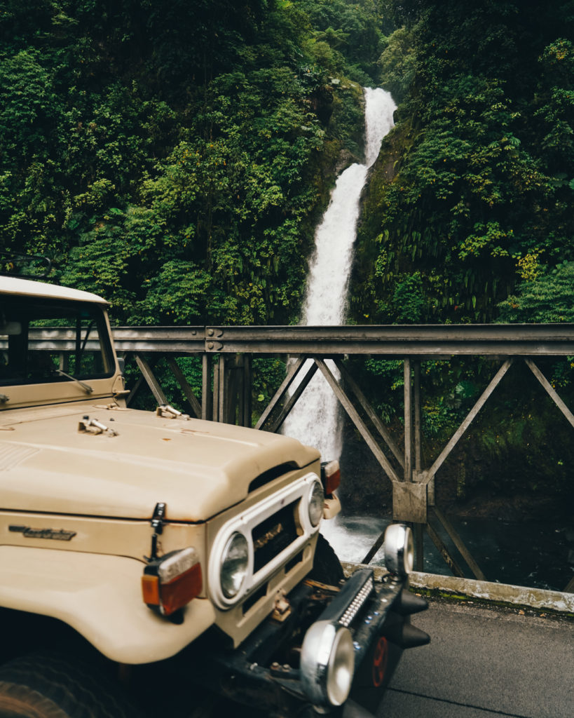 Rental car jeep in front of a waterfall in Costa Rica