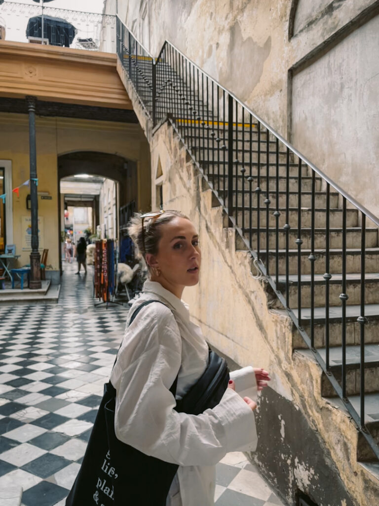 girl in aesthetic section of San Telmo sunday market in front of stairs